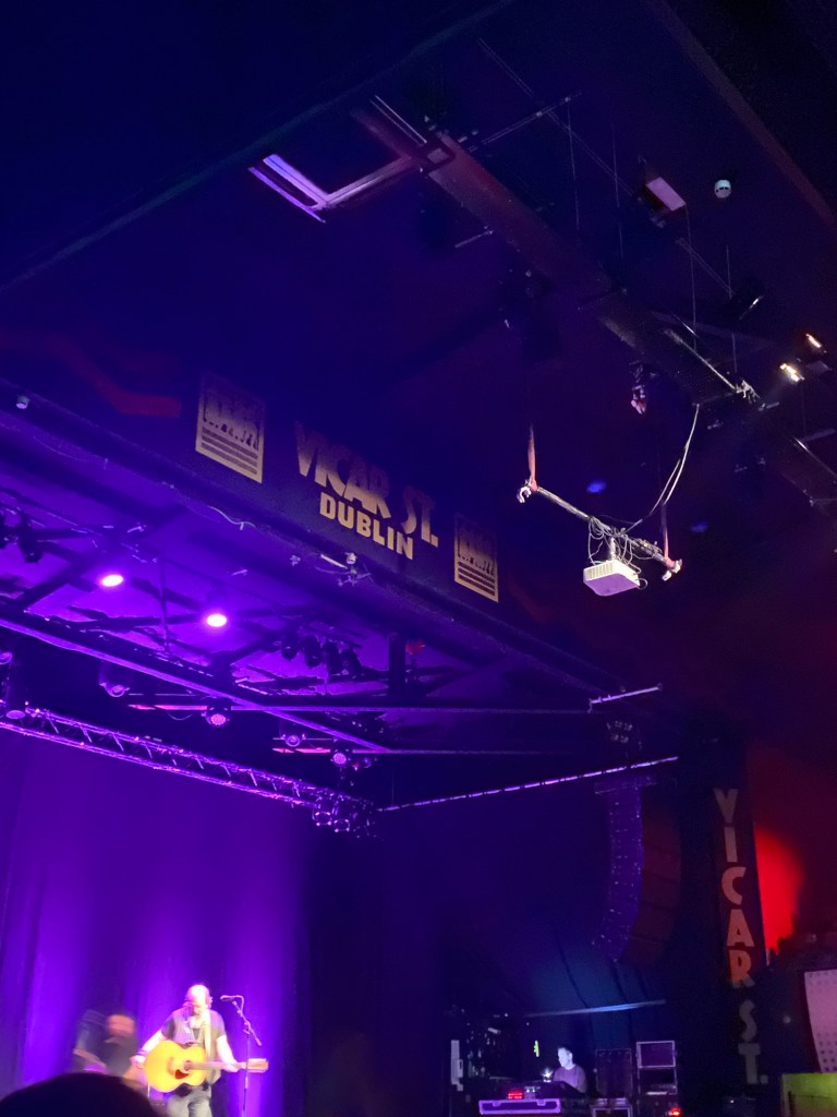 Bearded, long-haired man with an acoustic guitar onstage at Vicar St. 